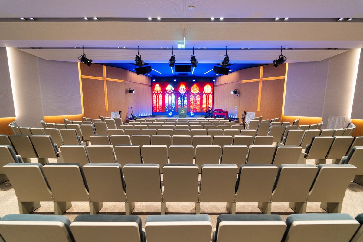Sala Maranatha cu amvonul și ecranul luminos, văzută dintre rânduri