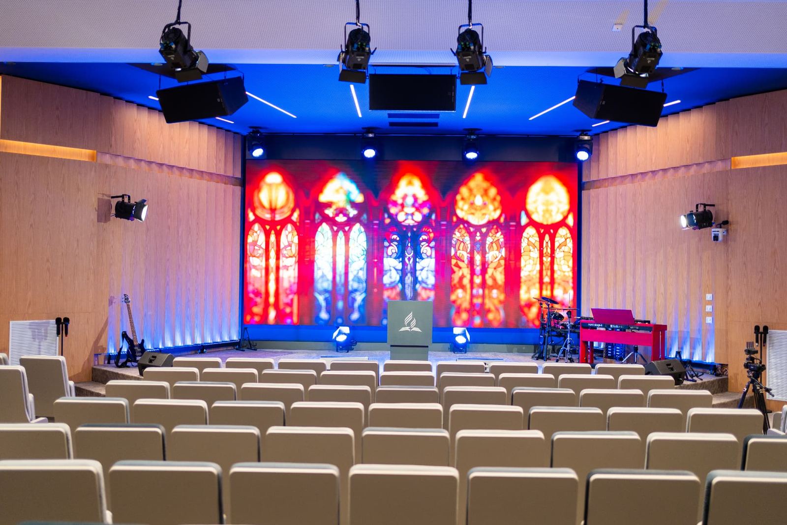 Sala Maranatha cu scena, ecranul cu vitralii luminoase și rândurile de scaune
